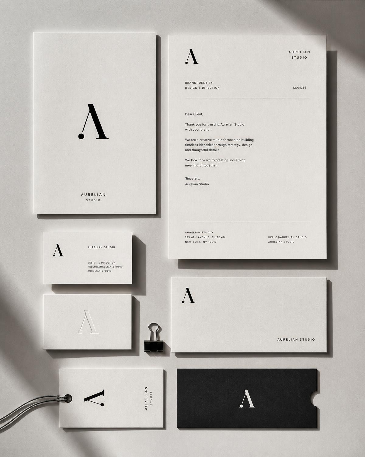 Monochrome brand identity stationery suite laid out on off-white paper